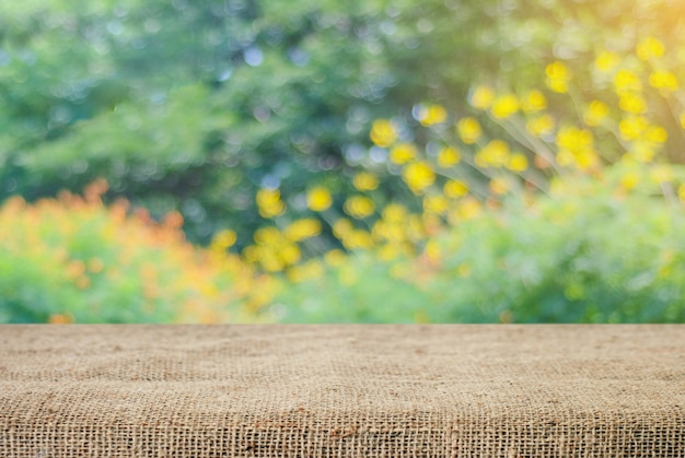 Mesa vazia e toalha de saco sobre árvore de borrão com fundo bokeh