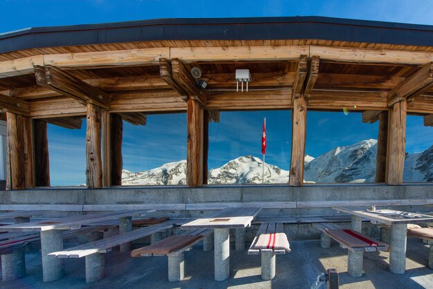 Mesas do restaurante em alta altitude com vista para a paisagem das geleiras refletidas em janelas de vidro na Suíça