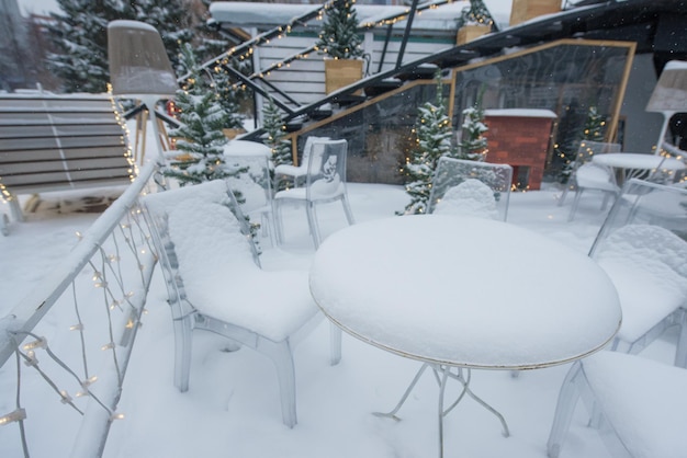 Mesas e cadeiras em um café coberto de neve ao ar livre