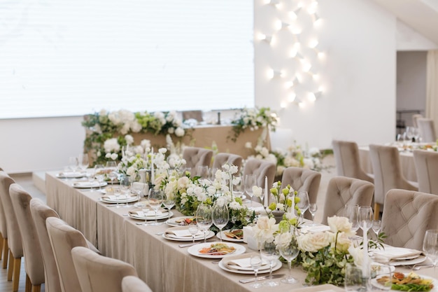 Mesas puestas en una boda de lujo Mesa para invitados Platos y bebidas Decoración floral sillas blancas y mesa Preparación de mesa de boda vista superior Foto horizontal