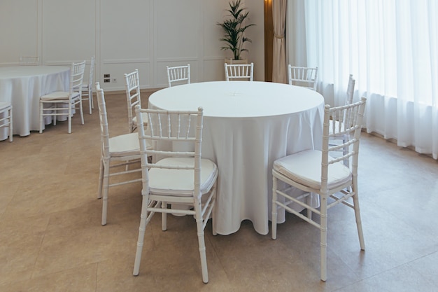 Mesas redondas brancas cobertas com uma toalha de mesa para festejar no restaurante parte da decoração e do interior