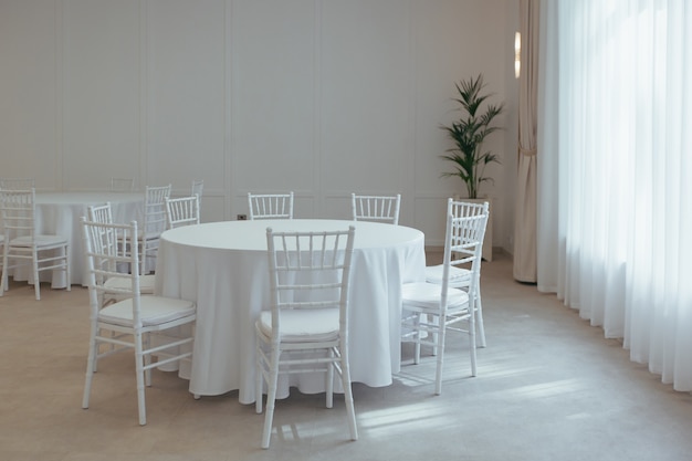 Mesas redondas brancas cobertas com uma toalha de mesa para festejar no restaurante parte da decoração e do interior