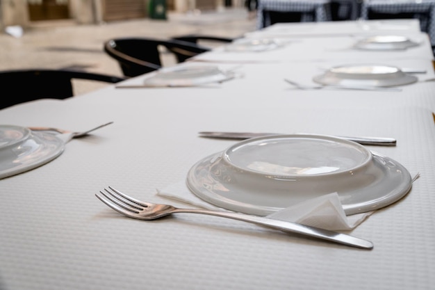Mesas de restaurante servidas en una calle listas para recibir a los invitados con los platos al revés