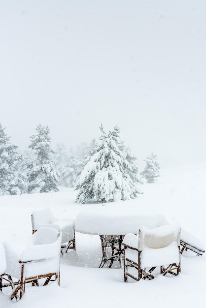 Las mesas y sillas de un restaurante están cubiertas por una fuerte nevada.