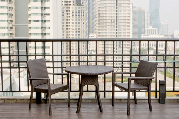 Mesas y sillas vacías en la terraza con vistas al edificio alto