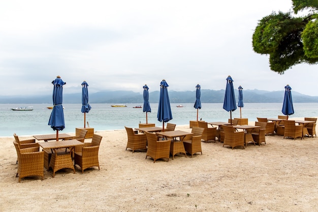 Mesas vacías del café de la playa. Paraguas plegados, falta de turistas.