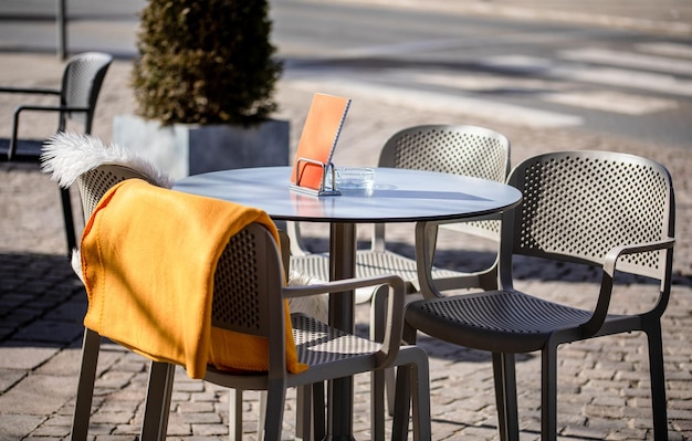 Mesas vazias do lado de fora entre as horas de almoço ao longo de um beco de paralelepípedos em uma cidade europeia, uma varanda, um café