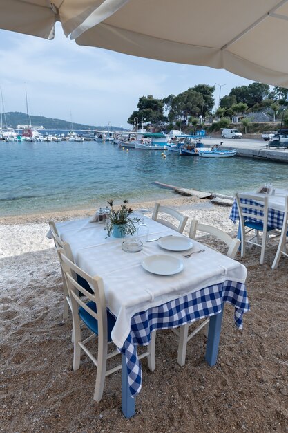 Mesas vazias em um café de praia em tons de azul em uma cidade mediterrânea