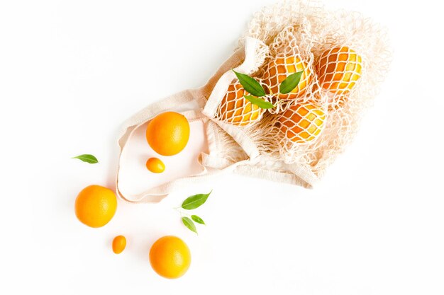Mesh-Einkaufstasche mit Orangen auf weißem Hintergrundmuster aus sommerlichen tropischen Früchten