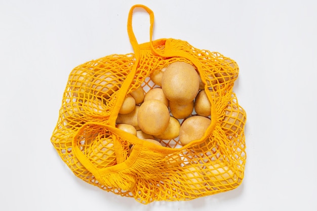 Mesh-Mehrwegbeutel mit frischen Kartoffeln Oranger Stringbeutel Rohkartoffeln Ansicht von oben Vegetarische Rohkost frisches Gemüse Bewusster Konsum Ohne Plastik Recycling