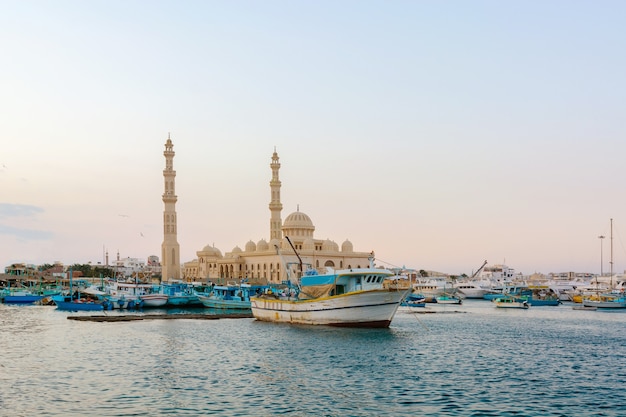 Mesquita e barcos de pesca ao pôr do sol em hurghada, egito