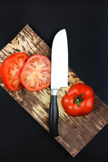 Messer schneiden eine Tomate Frische reife Gartentomaten auf Holzbrett