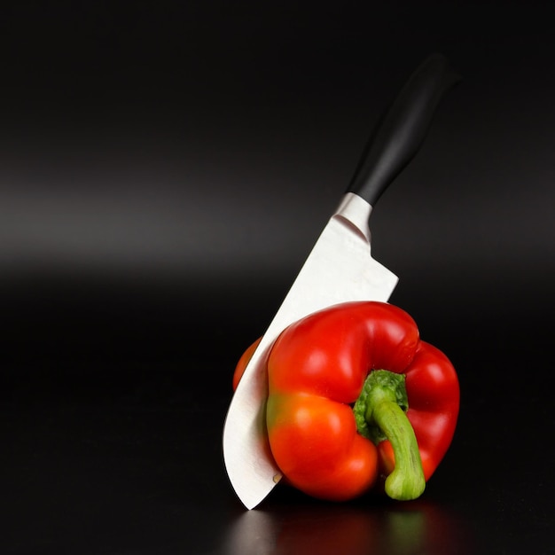 Messer schnitt rote Paprika auf schwarzem Hintergrund
