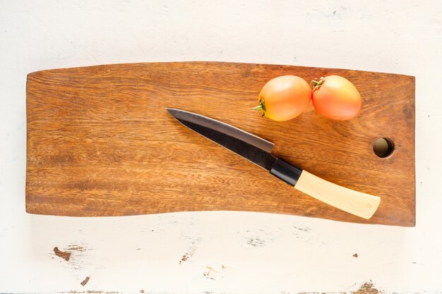 Messer und Tomate auf hölzernem Schneidebrett