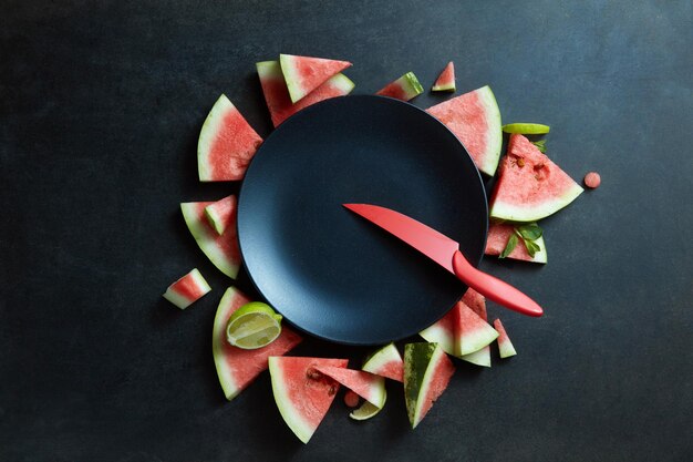 Messer und Wassermelonenscheiben in einem Kreis aus schwarzem Teller