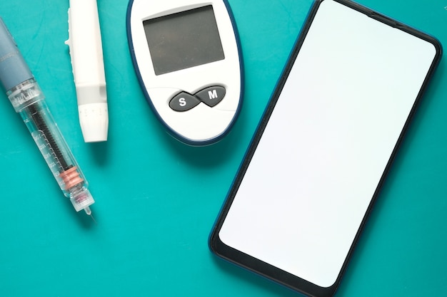 Messgeräte für Diabetiker, Insulin und Smartphone auf farbigem Hintergrund.