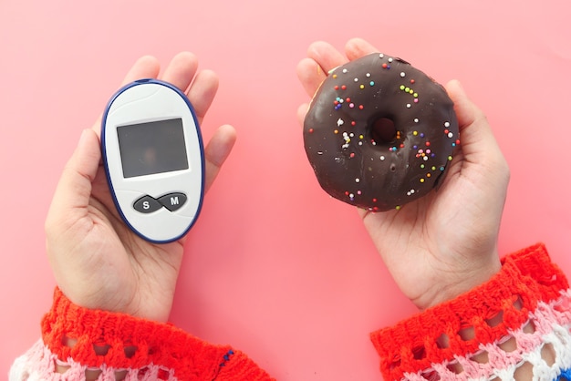 Messinstrumente und Donuts für Diabetiker an der Hand von Frauen