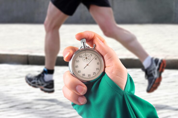 Foto messung der laufgeschwindigkeit eines athleten mit einem mechanischen stoppuhrzeiger mit einer stoppuhr auf dem hintergrund der beine eines läufers