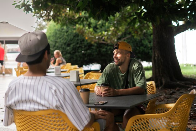 Mestiços amigos comendo comida de rua sentados à mesa