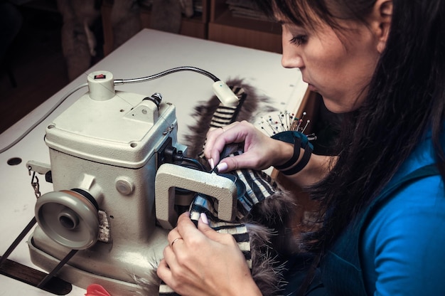 Mestre alfaiate feminina costurando a pele na máquina do peleiro