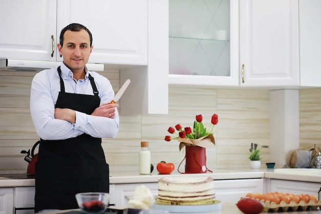 Mestre confeiteiro na frente de uma mesa. Cozinhar sobremesas em casa. O armênio dedica-se à confeitaria.