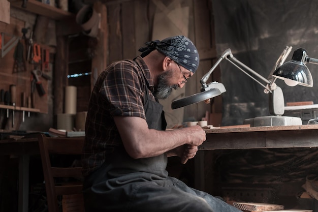 Mestre de colher em sua oficina com ferramentas e produtos de madeira. Foto de alta qualidade
