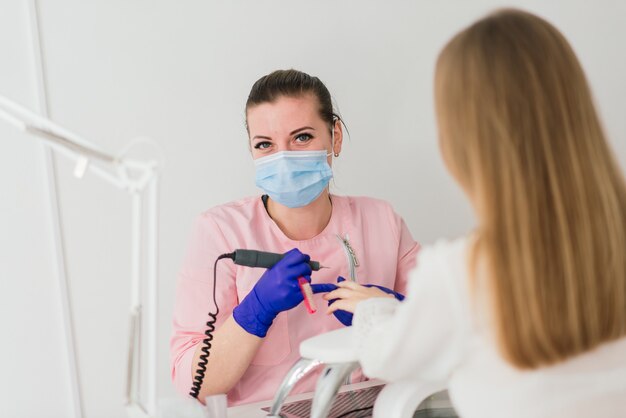 Mestre de manicure feminina em um salão de beleza trabalha com as mãos da cliente