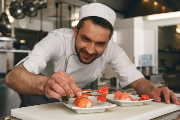 Mestre de sushi prepara sushi para servir na cozinha comercial moderna