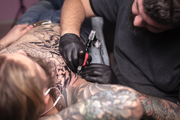 Mestre de tatuagem focado em seu trabalho em estúdio de tatuagem.