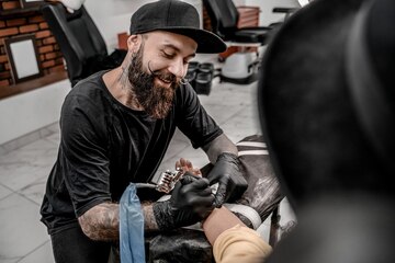 Mestre feminino faz tatuagem nas costas para cliente masculino no