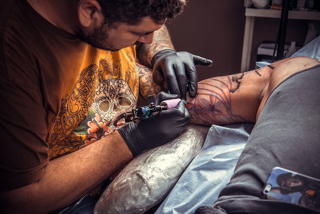 Mestre de tatuagem mostrando processo em estúdio de tatuagem