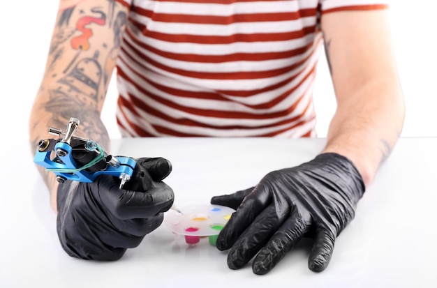 Foto mestre de tatuagem trabalhando em luvas médicas pretas com máquina de tatuagem de perto