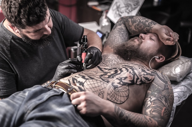 Mestre de tatuagem trabalhando em tatuagem profissional em estúdio