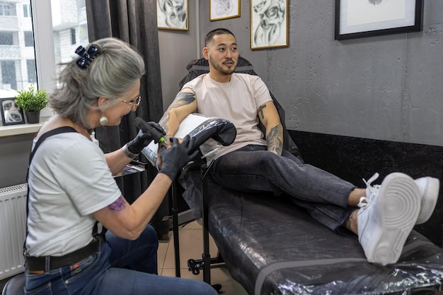 Mestre de tatuagem trabalhando em uma tatuagem para o cliente masculino