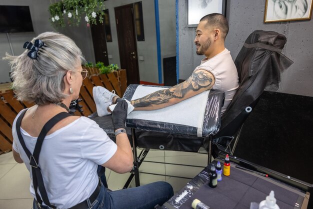 Mestre de tatuagem trabalhando em uma tatuagem para o cliente masculino