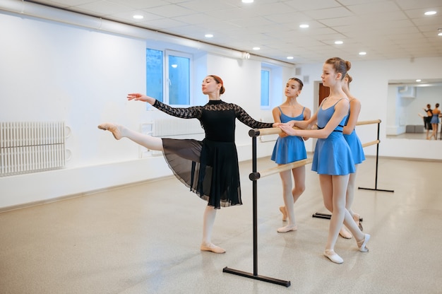 Mestre e jovens bailarinas exercitam-se na barra durante a aula. escola de balé, dançarinas em aula de coreografia, meninas praticando dança da graça