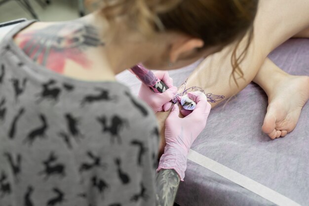 Mestre fazendo tatuagem em estúdio de tatuagem