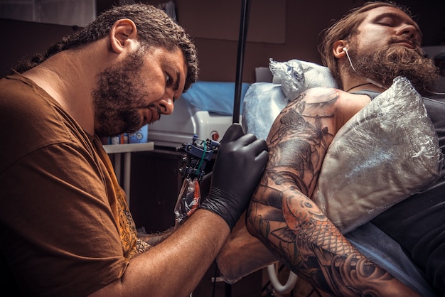 Mestre fazendo tatuagem no salão