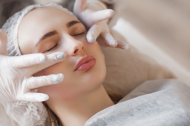 Foto mestre fazendo um procedimento cosmético para seu cliente. tratamento de cuidados com a pele. mulher fazendo um procedimento de cuidados do rosto.