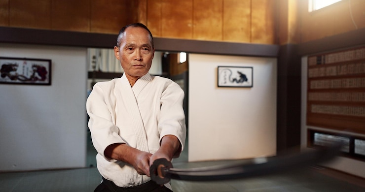 Foto mestre japonês de artes marciais ou treinamento com espada campeão de aikido ou professor de autodefesa sensei cinto preto ou katana em dojo lugar de esporte ou demonstração de arma por lutador maduro em combate