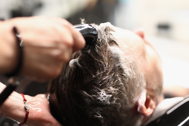 Mestre lava o cabelo da cliente com shampoo em salão de cabeleireiro