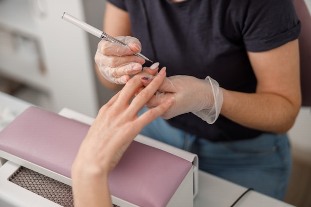 Mestre profissional de manicure está fazendo unhas para cliente em salão de beleza