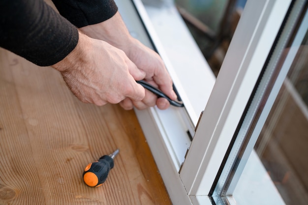 Mestre profissional na reparação e instalação de janelas, muda a junta de vedação de borracha nas janelas de pvc