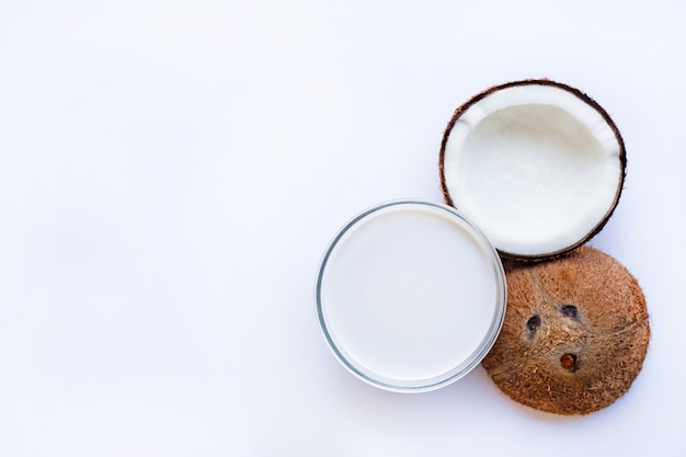 Metade de coco com tigela de vidro de leite de coco