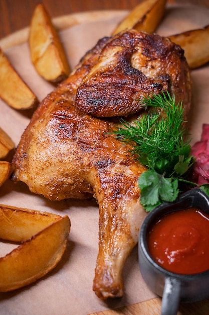 Metade de frango frito ou grelhado chamado tabaka servido com fatias de batata assada e ketchup