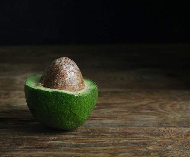 Metade de um abacate encontra-se sobre uma mesa de madeira.