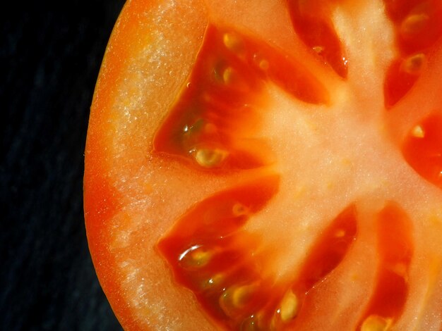 Metade de um grande tomate vermelho cortado Isolado em fundo preto Closeup Copiar espaço