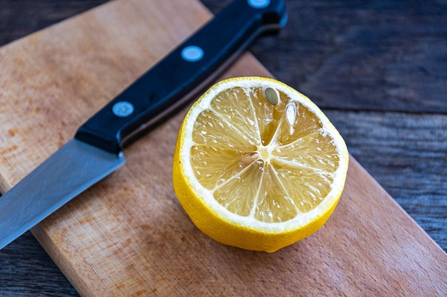 Metade de um limão em uma tábua com uma faca na mesa da cozinha.
