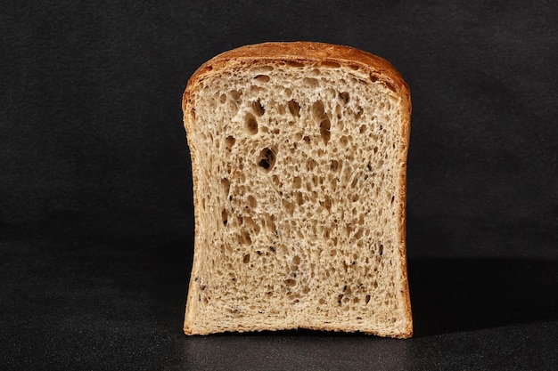 Metade de um pão cinzento saboroso fresco contra um fundo preto com espaço de cópia Closeup