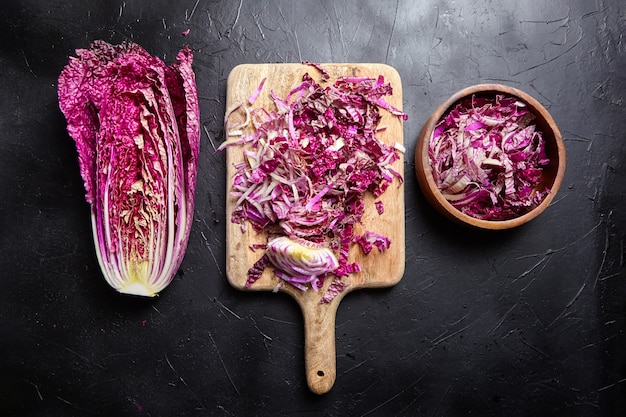 Metade do repolho napa vermelho picado na mesa preta, vista superior. cozinhar salada de vegetais, comida saudável